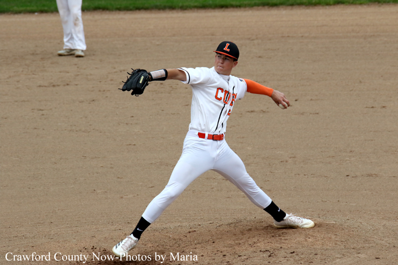 Baseball pitcher in a white uniform with orange accents winds up to throw on a dirt field.
