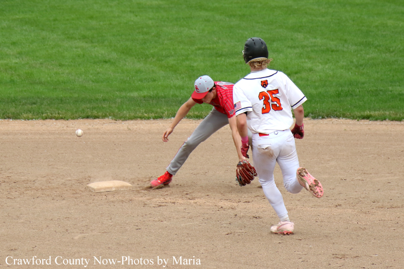 Infield action at second base: a fielder in red reaches for the ball as a runner in white (#35) rushes past.
