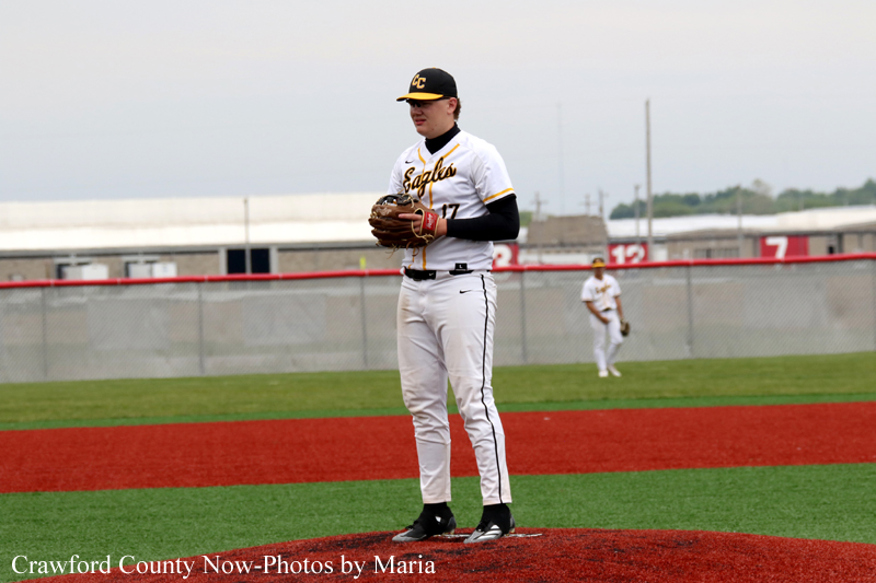 Baseball pitcher in a white uniform standing on the pitcher's mound with a glove ready in hand.