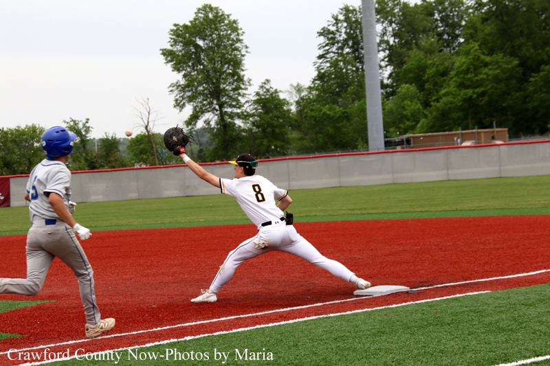 Baseball scene: a runner in white (number 8) slides into a base as a fielder in gray and blue glove reaches for the ball nearby on the dirt infield.