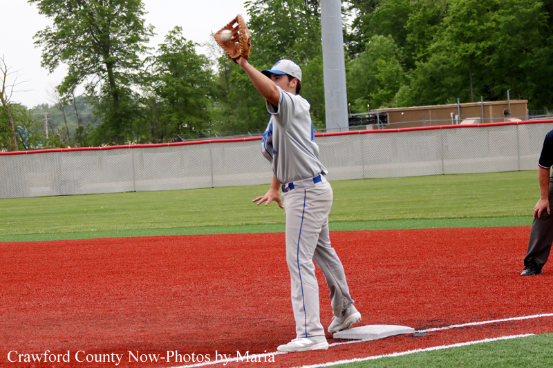Baseball pitcher in gray uniform winds up on the mound to throw a pitch with glove raised.