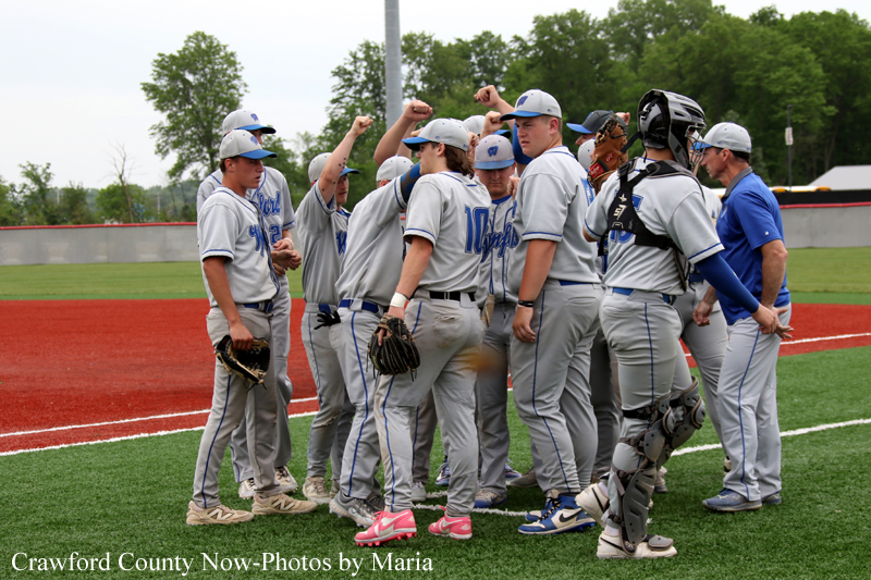 Baseball players in gray uniforms form a huddle on a field during practice or a game.