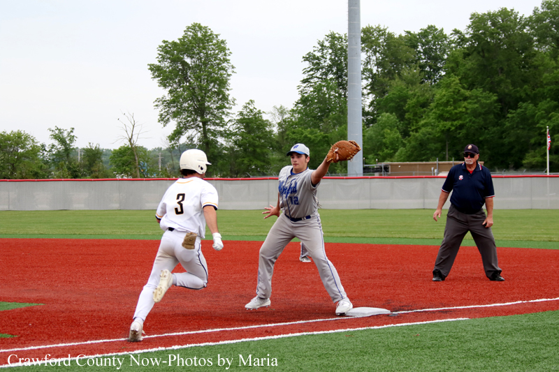 Baseball infield action: runner in white, #3, sprinting toward a base as a fielder in gray reaches with a glove; an umpire watches nearby.