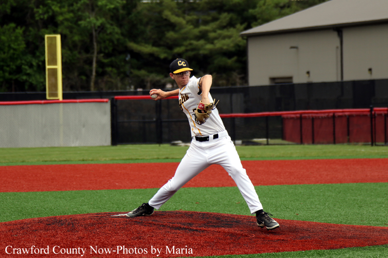 Baseball pitcher in a white uniform on the mound, throwing a pitch with his glove up and leg extended.