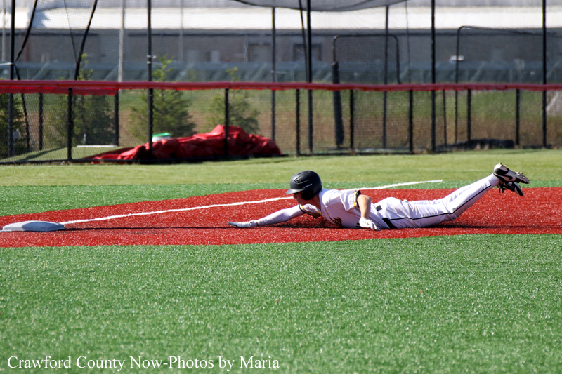 Baseball player slides into a base on a red infield strip during a game.