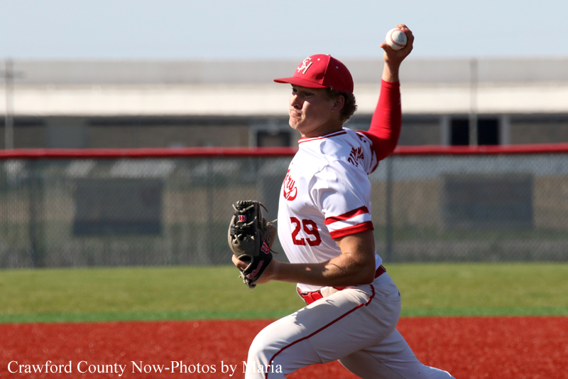 Baseball pitcher in a white and red uniform (No. 29) throwing a pitch on the red infield with glove on left hand and ball in right hand.