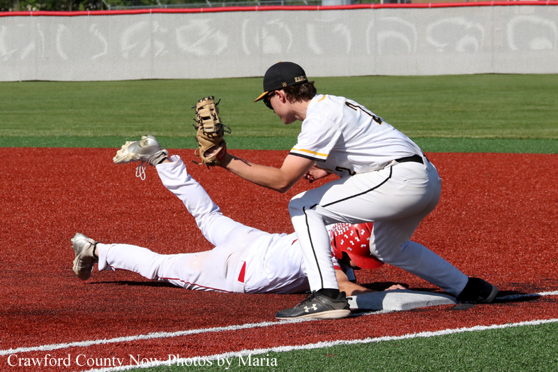 Baseball fielder in white tags a sliding runner at second base on a red dirt infield during a close play.