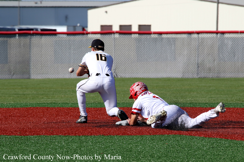 Baseball scene: fielder in white jersey number 16 reaches for a ball while a red-helmeted baserunner slides into the infield dirt near a base smudge of red clay.