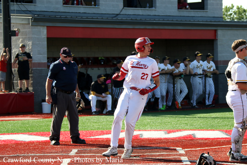 Baseball player in white and red uniform (#27) wearing a red helmet at home plate, looking toward the field.