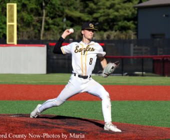 Baseball pitcher in white Eagles uniform delivering a pitch on the mound.