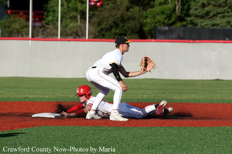 Baseball play: a fielder in white catches or prepares to catch the ball as a baserunner in red slides into second on red dirt.