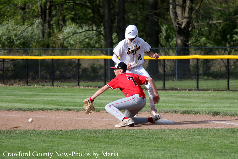 Baseball play at a base: a runner in red slides into the bag while a fielder in white covers second base.