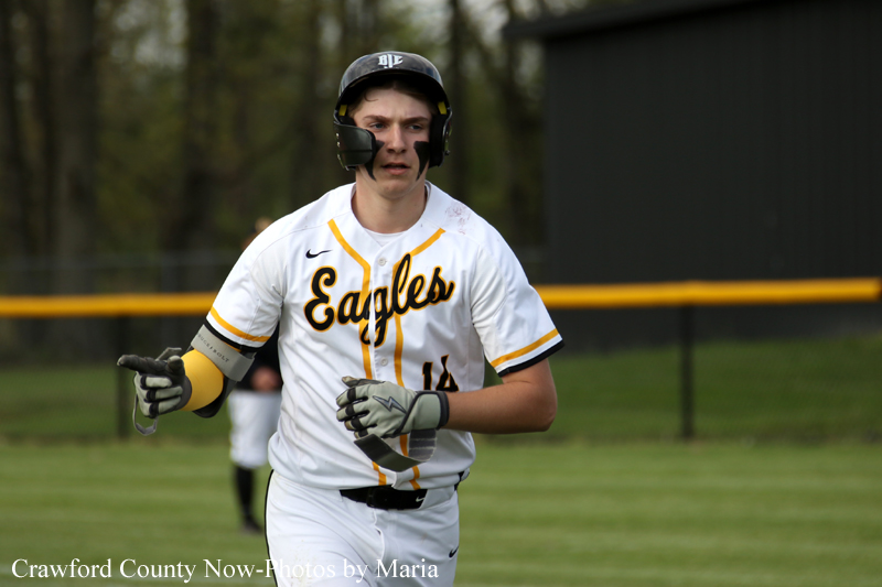 Baseball player in a white and yellow 'Eagles' uniform runs on the field during a game, wearing a helmet and gloves.