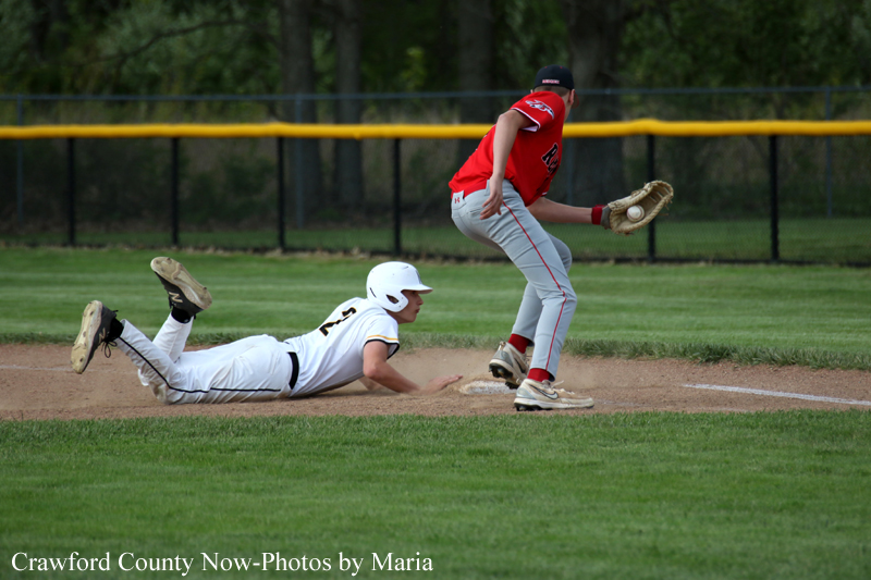 Baseball scene: a white-uniform slide into a base while a red-uniform fielder stands nearby with a glove ready to tag, on a grassy infield.