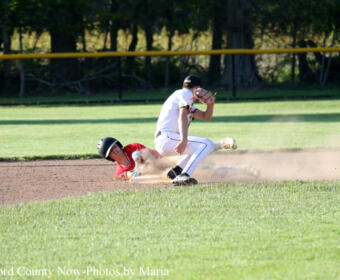 Baseball play on the infield: a white-uniform infielder tags a sliding runner in red as a dust cloud rises behind them.