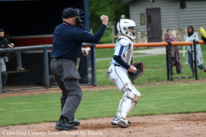 Baseball catcher in white protective gear and helmet celebrates with the umpire on the infield dirt.