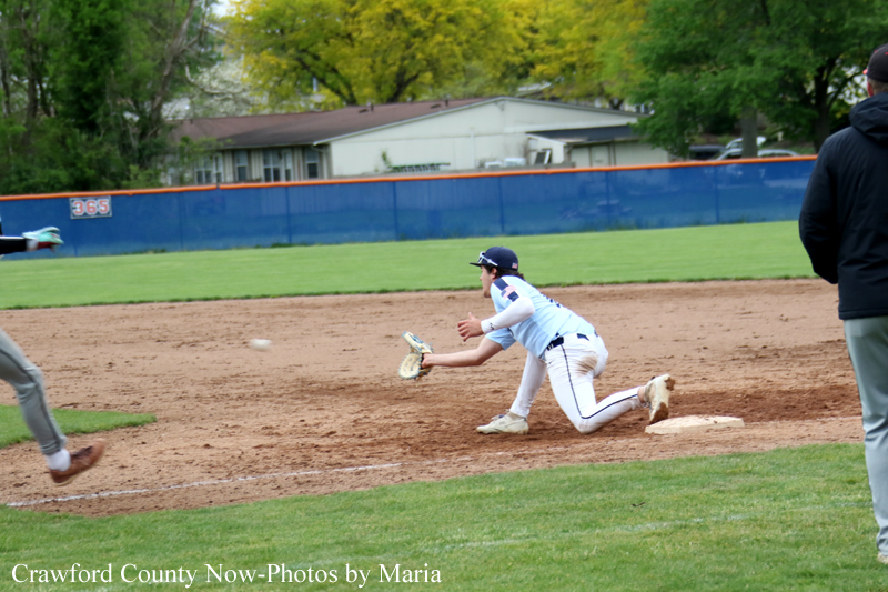 Baseball scene: fielder in white uniform diving to catch a ground ball near a base while another runner approaches from the left.