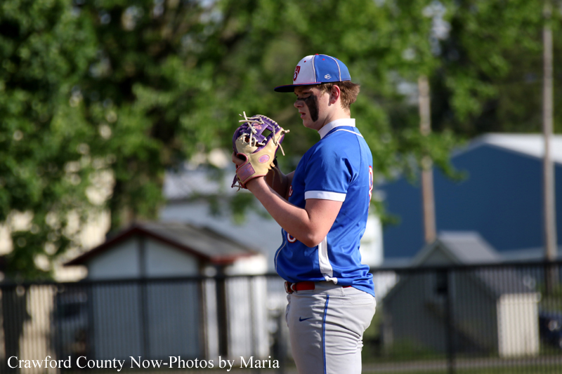 Baseball pitcher in a blue uniform with a glove up, ready to throw on the field.