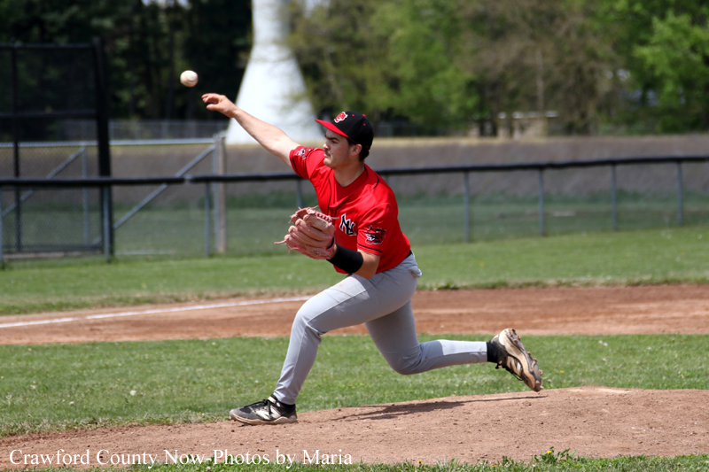 Baseball pitcher in a red uniform delivering a pitch on the mound