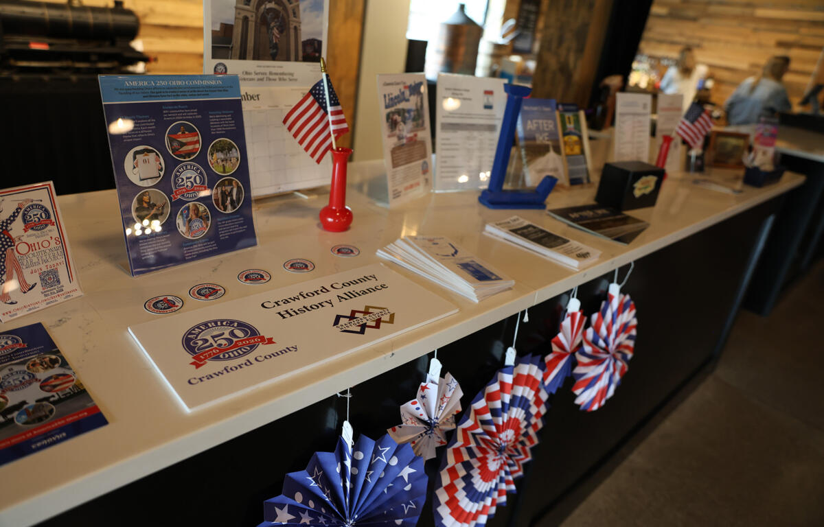 Patriotic display at a information desk with brochures, brochures stands, an American flag, and red‑white‑blue pinwheels on a white counter.
