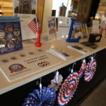 Patriotic display at a information desk with brochures, brochures stands, an American flag, and red‑white‑blue pinwheels on a white counter.