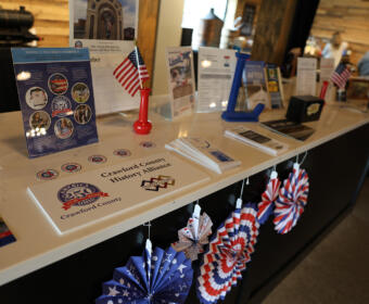 Patriotic display at a information desk with brochures, brochures stands, an American flag, and red‑white‑blue pinwheels on a white counter.