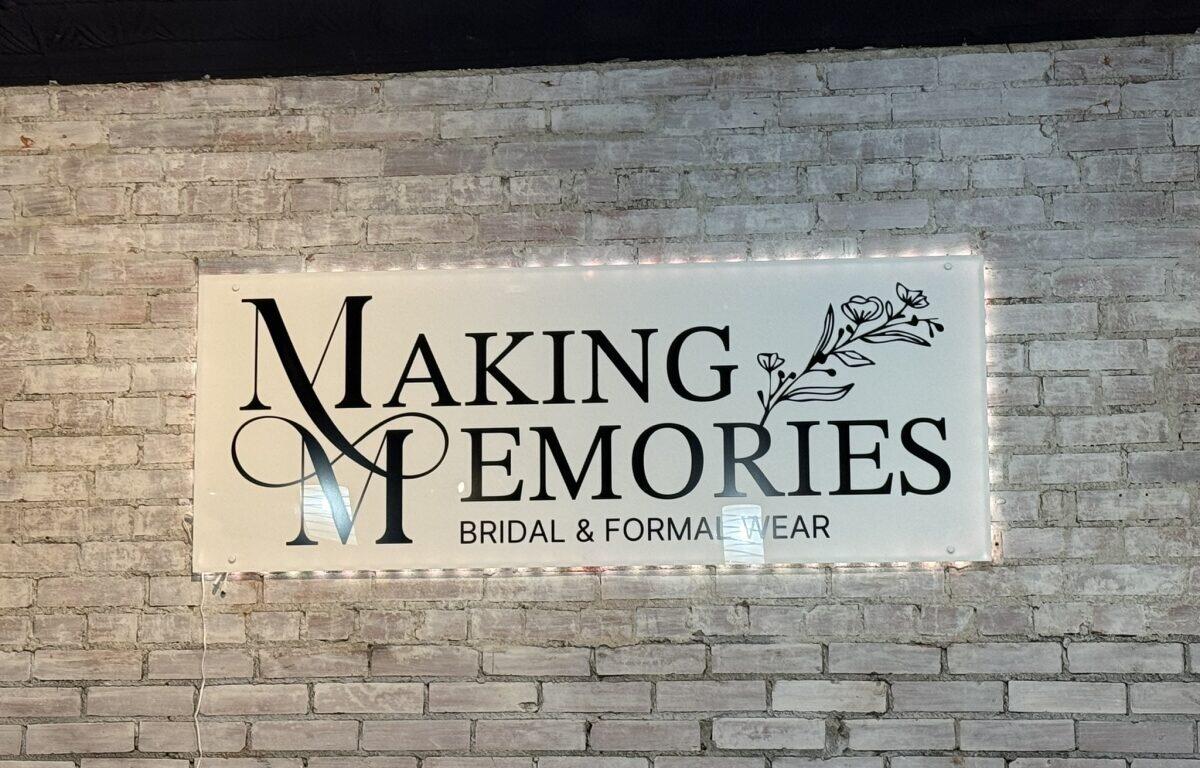 Sign on brick wall reading 'Making Memories' with decorative M and flowers; 'Bridal & Formal Wear' subtitle.