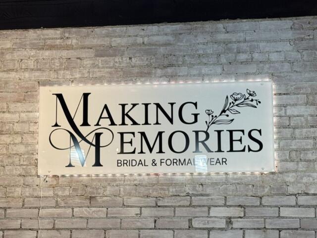 Sign on brick wall reading 'Making Memories' with decorative M and flowers; 'Bridal & Formal Wear' subtitle.
