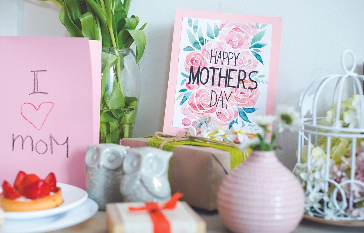 Pink Mother's Day cards with floral print and 'Happy Mother's Day' message among gifts and decor.