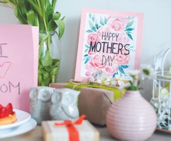 Pink Mother's Day cards with floral print and 'Happy Mother's Day' message among gifts and decor.