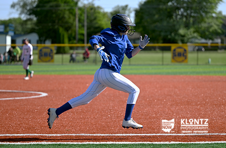 Young baseball player in a blue jersey and white pinstriped pants sprinting on the infield dirt, helmet on.