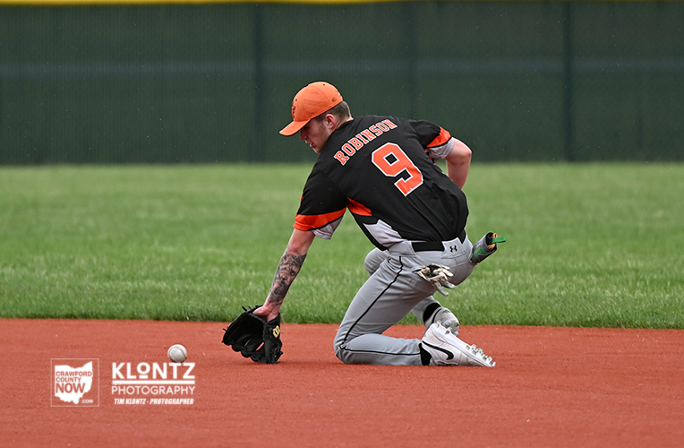 Baseball player in black and orange uniform, number 9, diving to field a ground ball on the infield dirt.