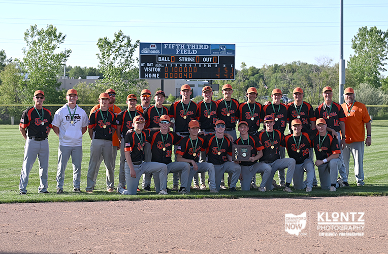 Baseball team posing with a trophy on the field; scoreboard in the background reads Fifth Third Field.