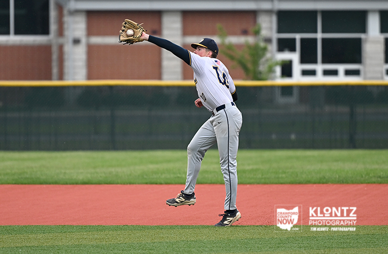 Baseball pitcher in white uniform mid-pitch on the mound, arm extended and left leg lifted.