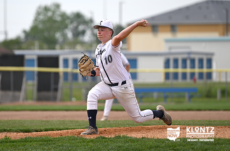 Young baseball pitcher in white uniform delivering a pitch on the mound, glove ready, focused on target.