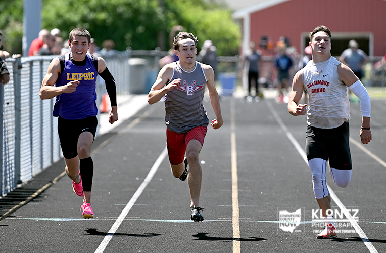 Three high school sprinters race toward the finish line on a track, wearing Leipsic, Columbus Grove, and team gray uniforms.