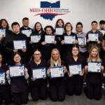 Group of students posing with certificates in front of a Mid-Ohio Educational Service Center banner.