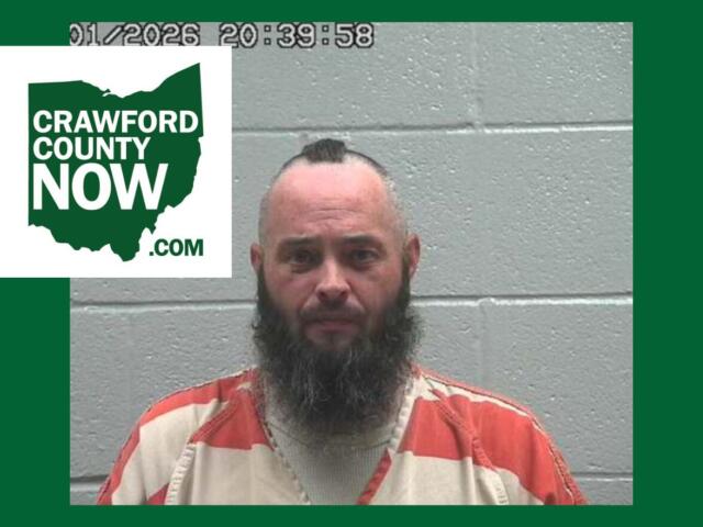 Mugshot of a bearded man in an orange prison jumpsuit against a gray cinder-block wall, with a Crawford County Now logo overlay on the left.