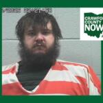 Mugshot of a bearded man in an orange jumpsuit against a gray wall; timestamp overlay and Crawford County Now logo in the corner.