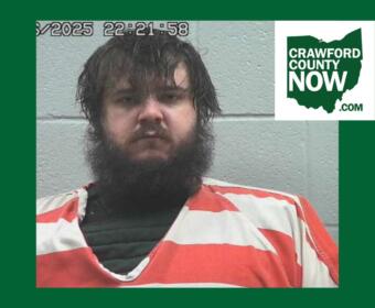 Mugshot of a bearded man in an orange jumpsuit against a gray wall; timestamp overlay and Crawford County Now logo in the corner.