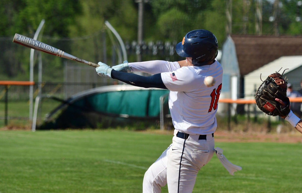 Baseball batter in a white uniform and blue helmet swings at a pitch, number 18 on his back, holding a Louisville Slugger bat.