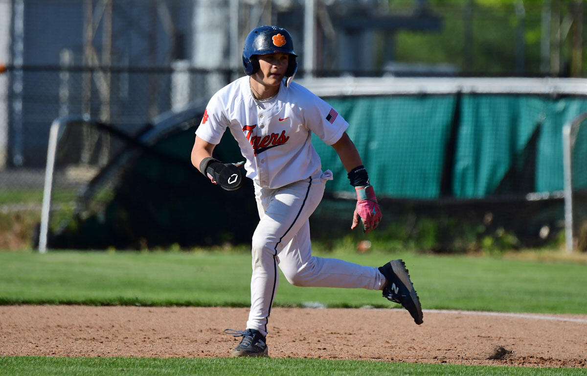 Baseball player in a white Tigers uniform runs on the infield with helmet and gloves visible.