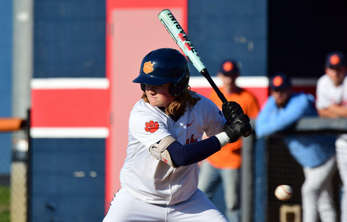 Female softball player in a Clemson uniform swinging a bat during a game.