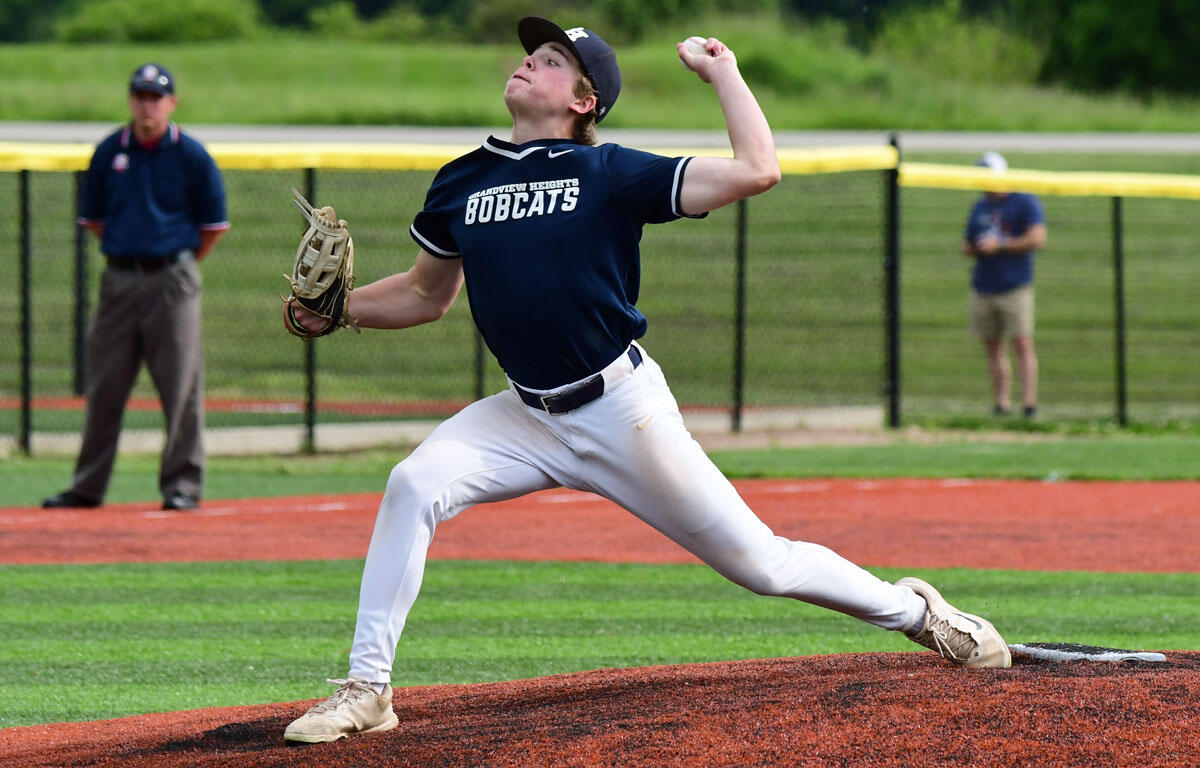 Baseball pitcher in navy Bobcats uniform mid-pitch on the mound with a glove ready to throw.