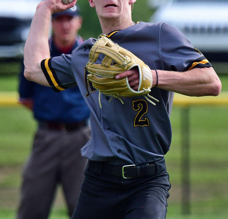 Baseball pitcher in gray uniform and cap, mid-throw with ball raised in his right hand and glove on his left.