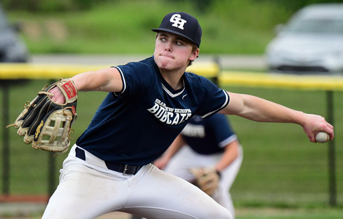 Right-handed baseball pitcher in a navy Bobcats uniform releasing a pitch with his glove extended and ball in his right hand.