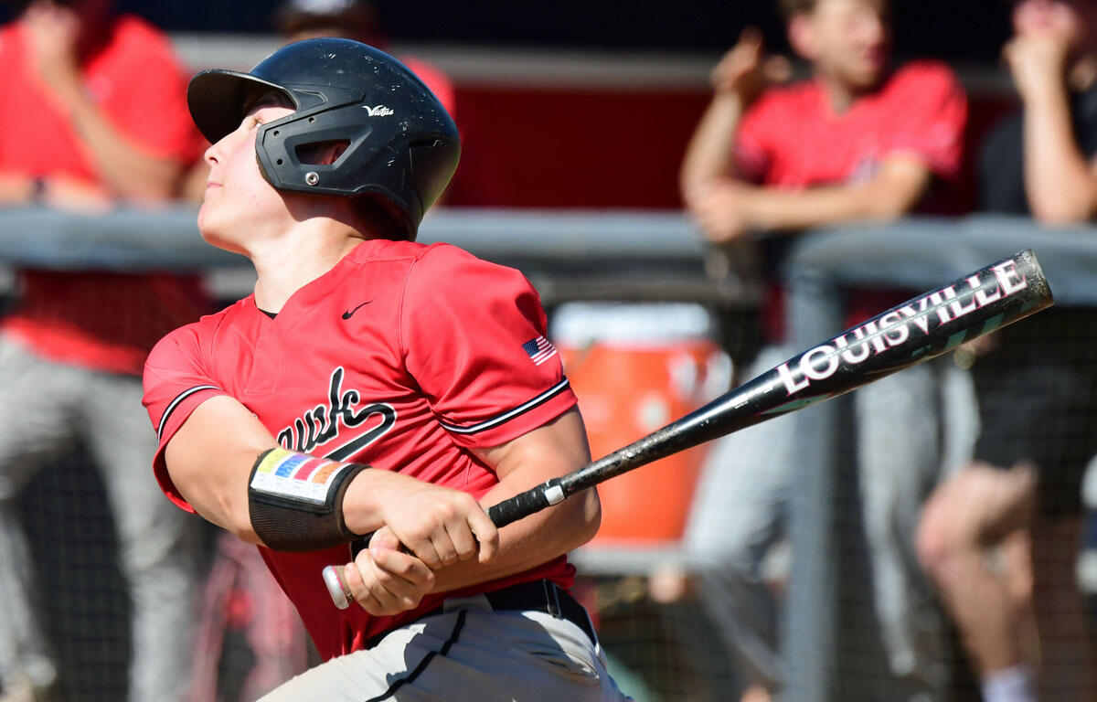 Baseball batter in a red jersey swings a Louisville bat during a game, helmet on, crowd watching.
