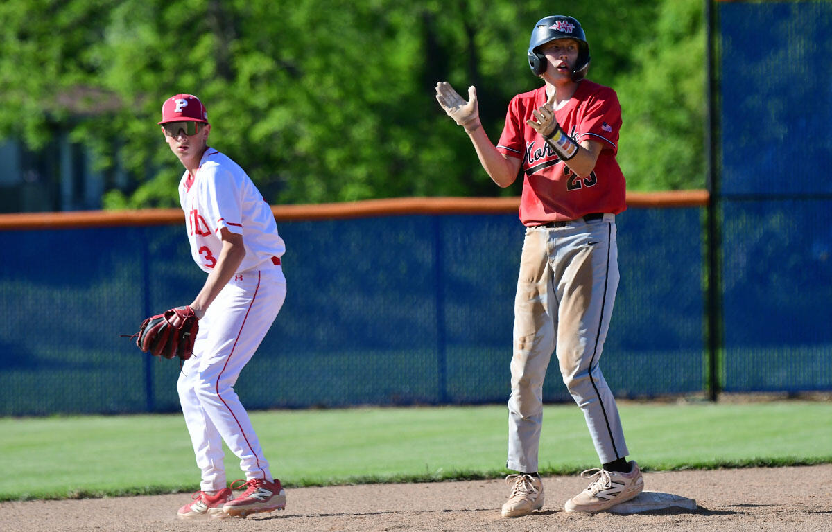 Two baseball players on the field: one in a white uniform with a glove at a base, the other in a red jersey clapping near the base.