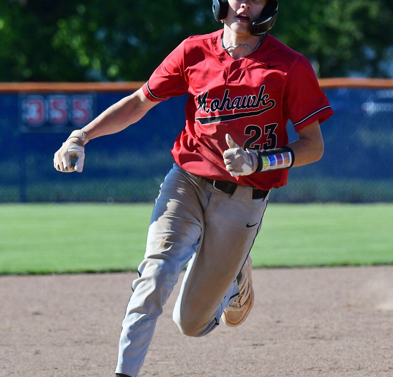 Baseball player in a red jersey and helmet sprinting on the infield dirt, number 23 visible.