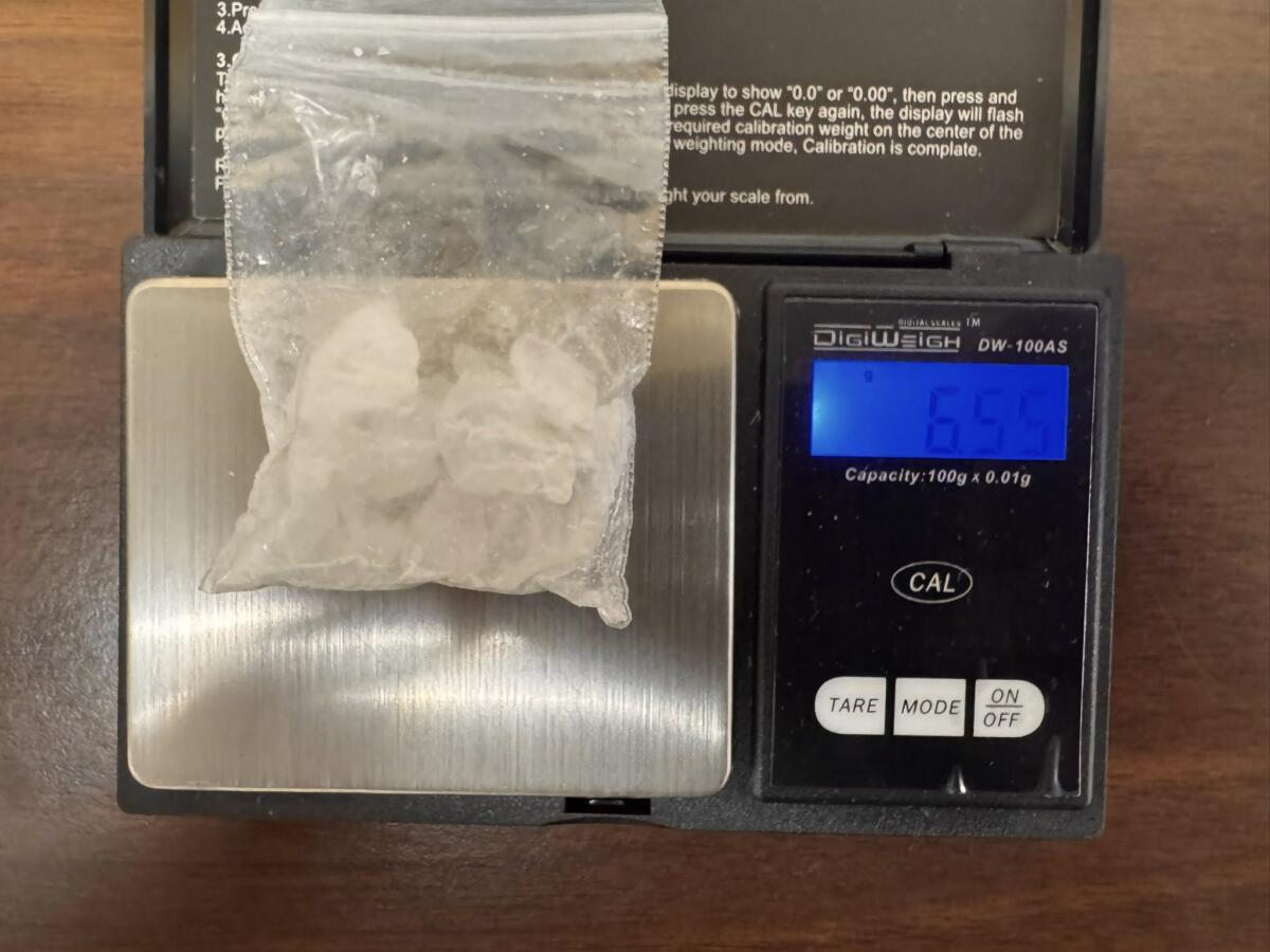 Digital kitchen scale with a small resealable bag of white powder on the weighing platform.